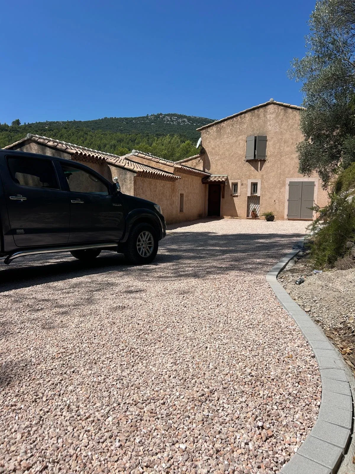 Cour d’une bastide recouverte de gravier rose stabilisé, bordure en pierre