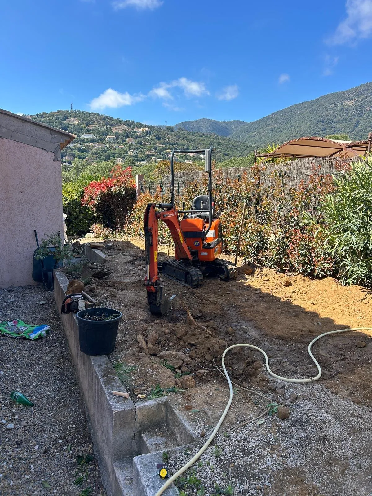 Avant : terrain retourné, mini-pelle au travail le long d’une bordure