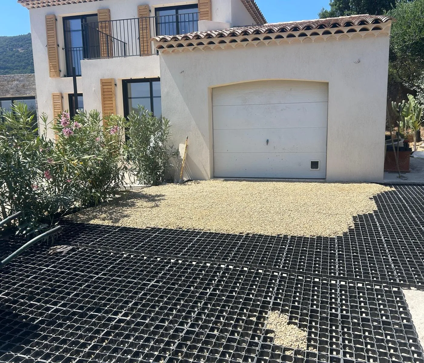 Dalles alvéolées en cours de remplissage de gravier devant un garage